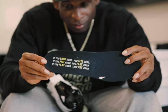 Deion Sanders hold Nike Diamond Turf 3 shoes